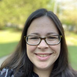 Brunette with black rectangular glasses, blurred park background